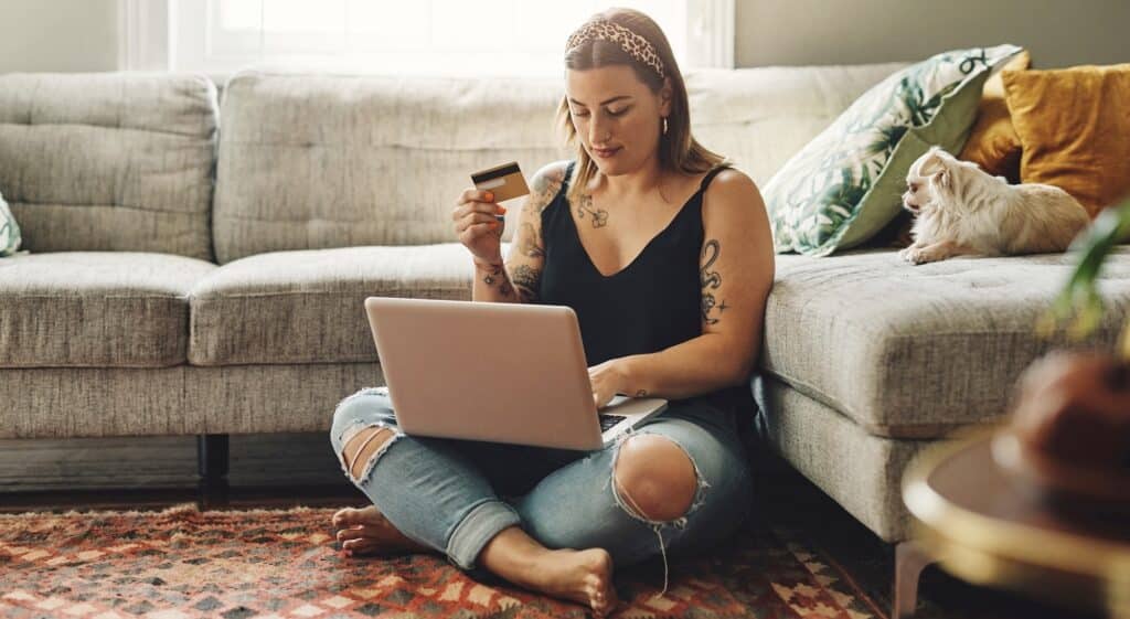 Gen Z woman holding debit card using a computer for banking with her credit union